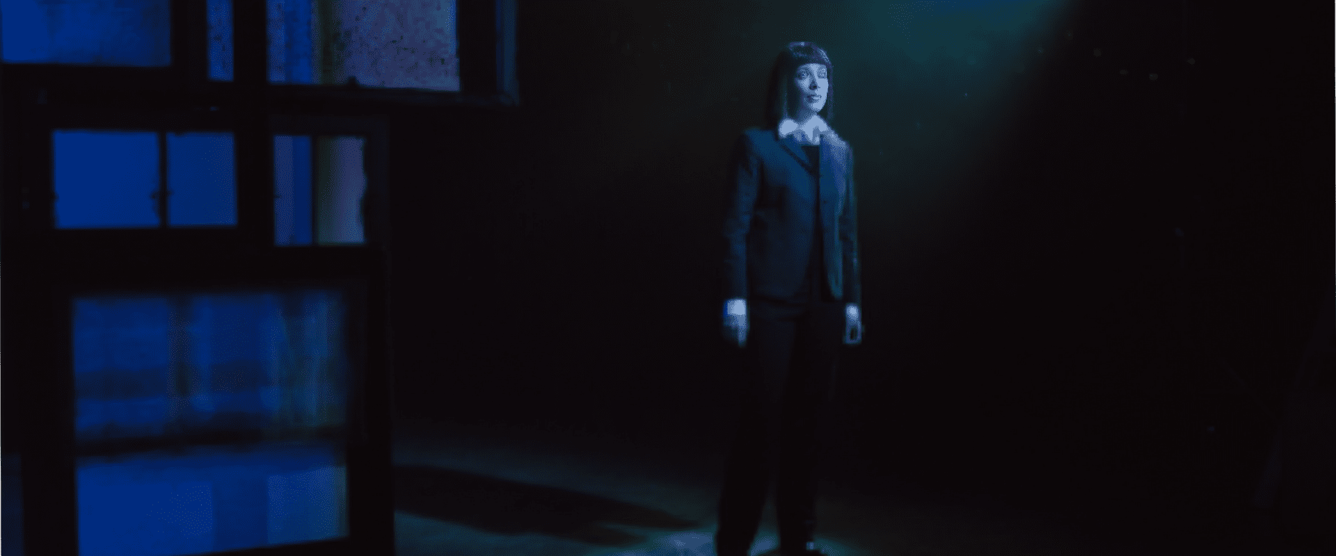 A man in a suit standing in the dark.