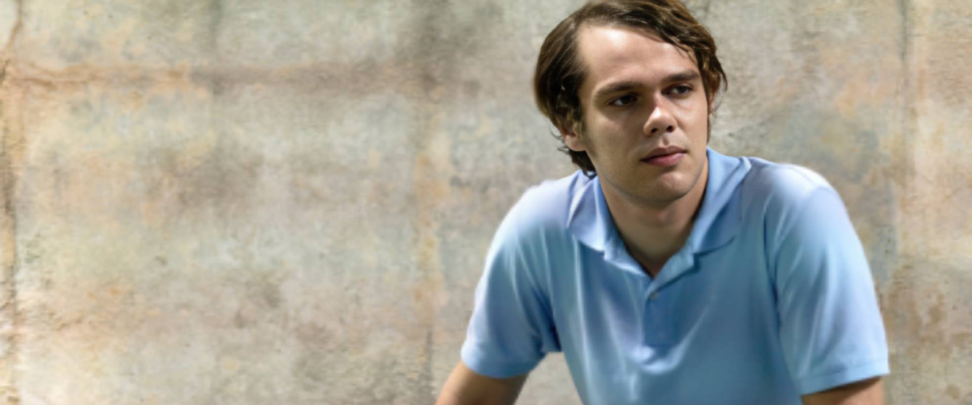 A man in blue shirt sitting on the ground.